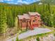Beautiful mountain home with a red roof and stone accents surrounded by lush green trees and natural landscape at 322 Davis Ct, Breckenridge, CO 80424