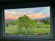 Window view with vibrant sunset sky over lush green landscape with trees at 87 Deerwood Dr, Littleton, CO 80127