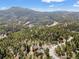 Breathtaking aerial shot showcasing a home surrounded by a lush green forest and winding roads at 11648 Broken Arrow Dr, Conifer, CO 80433