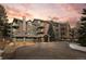 Inviting exterior of a multi-story condo building with stone accents and manicured landscaping against a colorful sunset at 31719 Rocky Village Dr # 317, Evergreen, CO 80439