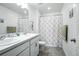 Well-lit bathroom with double sinks, white cabinets, and a shower-tub combination with floral curtain at 27504 E 1St Pl, Aurora, CO 80018