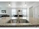Granite kitchen island with a stainless steel sink and views of the dining and living area at 27504 E 1St Pl, Aurora, CO 80018