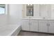 Elegant bathroom with double vanity, white cabinets, and a separate tub at 1102 Ridgefield Dr, Berthoud, CO 80513
