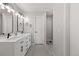 A modern bathroom with double sinks, white cabinets, black hardware and light gray wood-look floors at 3656 E 134Th Dr, Thornton, CO 80241