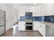 Modern kitchen featuring stainless steel appliances, white cabinets, and striking blue backsplash at 3656 E 134Th Dr, Thornton, CO 80241