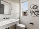 Sleek bathroom with a modern vanity, toilet, and a window, featuring unique wall decor at 8336 E 35Th Ave, Denver, CO 80238