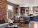 Open concept kitchen features brick accent walls, quartz countertops, floating shelves, and eat-in dining area at 8336 E 35Th Ave, Denver, CO 80238
