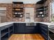 The kitchen has exposed brick walls, an undermount sink, open shelving, and modern cabinetry at 8336 E 35Th Ave, Denver, CO 80238
