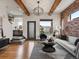 The living room boasts hardwood floors, exposed beams, brick accent wall, and modern furnishings at 8336 E 35Th Ave, Denver, CO 80238