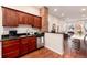 Open kitchen with modern appliances, cherry cabinets, granite countertops, and a view into the dining and living areas at 3220 W 24Th Ave, Denver, CO 80211