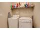 Functional laundry room with a washing machine, dryer, storage shelf and ironing board at 9279 Merino Ct # D, Littleton, CO 80125