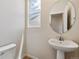 Bathroom featuring a pedestal sink and fixtures, a large round mirror, and a view to the outdoors at 42754 Calusa Pines Rd, Elizabeth, CO 80107