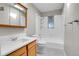 Bright bathroom with a shower-tub, hexagon tile flooring, a skylight, and a wood vanity with modern fixtures at 891 Ursula St, Aurora, CO 80011