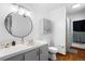 Bright bathroom featuring a round mirror, tiled counter, and gray cabinets at 16359 W 10Th Ave # X6, Golden, CO 80401