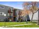 Gray apartment building with balconies, patios, lawn, and mature trees on a sunny day at 16359 W 10Th Ave # X6, Golden, CO 80401