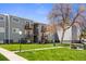 Gray apartment building with balconies, patios, lawn and mature trees on a sunny day at 16359 W 10Th Ave # X6, Golden, CO 80401