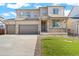 Charming home featuring a front porch, stone accents, well-maintained lawn, and a two-car garage at 13489 Valentia Pl, Thornton, CO 80602