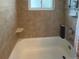 Tiled bathtub and shower combo with a window in a well lit bathroom at 4383 S Eagle Cir, Aurora, CO 80015