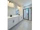Modern bathroom featuring dual sinks, tiled floors, and a glass-enclosed shower at 9662 Browns Peak Cir, Littleton, CO 80125