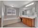 Bright bathroom featuring soaking tub, crystal light fixture, and vanity at 2485 Greensborough Cir, Highlands Ranch, CO 80129