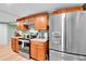 Well-lit kitchen with stainless steel refrigerator, wooden cabinets, and granite countertops at 2580 Valley View Dr, Denver, CO 80221