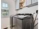 Well-lit laundry room with modern gray units, window, and overhead storage space at 8144 W 81St Dr, Arvada, CO 80005