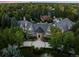 Aerial view of estate home displaying landscaped grounds, circle drive, mature trees, and pool at 5 Mockingbird Ln, Cherry Hills Village, CO 80113