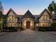 Grand front entrance of stone estate boasts arched doorway, copper roof, and impeccable landscaping at 5 Mockingbird Ln, Cherry Hills Village, CO 80113