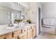 Bright bathroom featuring a double sink vanity, large mirror, and a glass-enclosed shower at 1469 S Ulster St, Denver, CO 80231