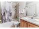 Bathroom with shower-tub combo, wood vanity, white sink and forest-themed shower curtain at 1469 S Ulster St, Denver, CO 80231