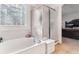 Bright bathroom showing a soaking tub next to the shower, with tiled walls and glass block window at 1469 S Ulster St, Denver, CO 80231