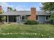 Home exterior featuring a covered patio, brick chimney, green lawn, and mature trees at 523 E Long Ct, Littleton, CO 80122