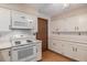 Efficient kitchen layout featuring bright white cabinets, laminated floors, and white appliances at 523 E Long Ct, Littleton, CO 80122