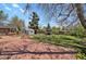 Open backyard with a brick patio, fire pit, and grassy area, surrounded by mature trees at 440 Balsam St, Lakewood, CO 80226