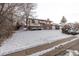 Two story home with brick and tan siding, a covered entry and a snow-covered yard and street in this winter scene at 1520 Phillips Dr, Northglenn, CO 80233