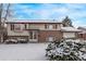 Charming two-story home featuring a brick facade and a cozy bay window, all dusted with a fresh layer of snow at 1520 Phillips Dr, Northglenn, CO 80233