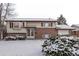 Charming two-story home featuring a brick facade and a cozy bay window, all dusted with a fresh layer of snow at 1520 Phillips Dr, Northglenn, CO 80233