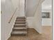 Carpeted staircase leading to the upper level with a wooden handrail and a visible door at the top at 1520 Phillips Dr, Northglenn, CO 80233