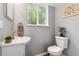 Updated powder room with white fixtures, stylish decor, and a painted brick accent wall for added charm at 1713 S Holland St, Lakewood, CO 80232