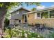 Charming home with a brick facade, complemented by lush landscaping and a cozy outdoor seating area at 1713 S Holland St, Lakewood, CO 80232