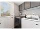 A laundry room featuring a white door, gray walls, cabinets, and Samsung washer and dryer appliances at 1713 S Holland St, Lakewood, CO 80232