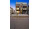 Townhouse featuring a stylish facade with grey brick, dark metal, and cantilevered balcony, enhanced by warm lighting at 2326 Eliot St # 7, Denver, CO 80211