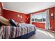 Bright bedroom showcasing a large window, plush carpet, and vibrant red walls at 6024 W Colorado Ln, Lakewood, CO 80232