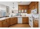 Well-lit kitchen with wood cabinetry, white appliances, and a view into the adjacent living area at 6024 W Colorado Ln, Lakewood, CO 80232