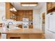 Well-lit kitchen with wood cabinetry, white appliances, and an island sink at 6024 W Colorado Ln, Lakewood, CO 80232