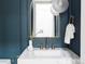 Stylish powder room featuring brass fixtures, blue walls with wainscotting, statement lighting, and a modern sink at 1 Winged Foot Way, Littleton, CO 80123