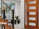 Staircase near a wood and glass paneled door with black hardware and an art piece in the background at 1 Winged Foot Way, Littleton, CO 80123