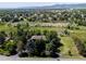 Aerial view of a property with a home, mature trees, and surrounding landscape in a residential area at 12196 W Belleview Dr, Littleton, CO 80127