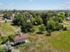Aerial view of a barn with a nearby house surrounded by grassy fields and trees at 12196 W Belleview Dr, Littleton, CO 80127