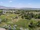 Scenic aerial shot showcasing a large grassy property with distant mountain views, and mature trees surrounding the home at 12196 W Belleview Dr, Littleton, CO 80127